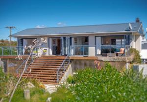 a house with wooden stairs in front of it at Spectacular Ocean View at Ruby Bay in Mapua