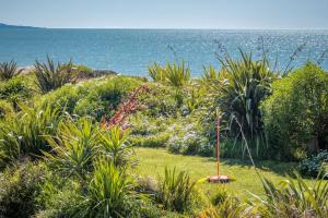 a garden with plants and the ocean in the background at Spectacular Ocean View at Ruby Bay in Mapua