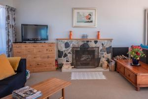 a living room with a fireplace and a tv at Spectacular Ocean View at Ruby Bay in Mapua