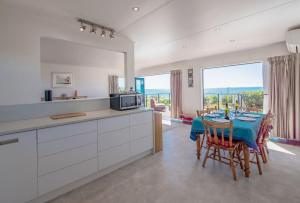 a kitchen and dining room with a table and chairs at Spectacular Ocean View at Ruby Bay in Mapua