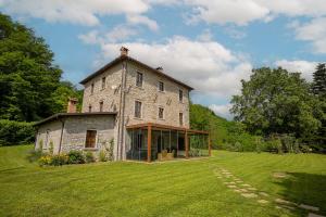 an old stone house on a grass field at Villa Casa di Pietra en el norte de Lucca, Toscana in Camporgiano