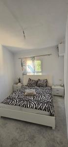 a zebra print bed in a white bedroom at ain draham sejour 1 familles seulement in Aïn Draham