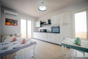 une cuisine avec des armoires blanches et une table avec des chaises dans l'établissement Residenza NETTUNO, à Tropea