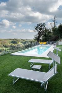 a swimming pool with two benches in the grass at Belavista in Scurzolengo