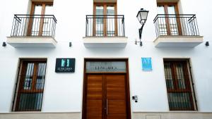a white building with a wooden door and windows at Aparthotel Luz de Gades - Suites Spa Gym - Adults Only in Cádiz