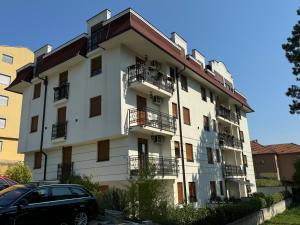 a white building with balconies and a car parked in front at BellaVita Apartman in Vrnjačka Banja