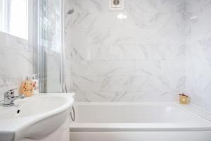 ein weißes Badezimmer mit Badewanne und Waschbecken in der Unterkunft Lovely 4 Bedrooms House Near Romford Station With Parking in Romford + 15 Fotos