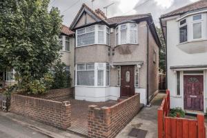 ein Haus mit einem Steinzaun davor in der Unterkunft Lovely 4 Bedrooms House Near Romford Station With Parking in Romford