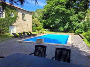 a swimming pool in front of a house with chairs around it at Quinta de Bóco in Arouca