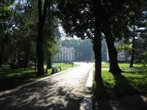 a path in a park with a bench and trees at Ultra Central Park Apartments in Chişinău