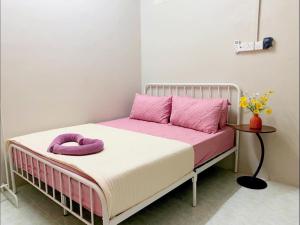a bedroom with a bed with pink pillows and a table at SOFEA HOMESTAY in Pantai Cenang