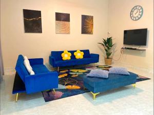 a living room with two blue couches and a tv at SOFEA HOMESTAY in Pantai Cenang