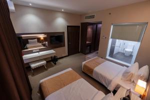 a hotel room with two beds and a desk at Hotel Tamara Melaka in Malacca