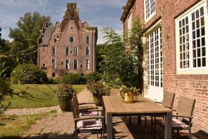a wooden table and chairs in front of a building at De Orangerie in Loenen