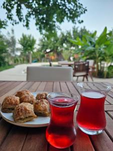 a plate of food on a wooden table with two drinks at Çıralı Nun Bungalove in Cıralı