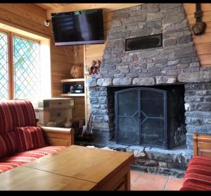 a living room with a stone fireplace with a television at Chalet épicanthus 8 chambres praloup 1600 in Uvernet