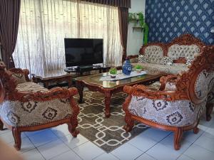 a living room with a couch and two chairs and a tv at Kalia Cottage in Batu