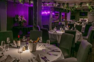 ein Esszimmer mit Tischen und Stühlen und violetter Beleuchtung in der Unterkunft Best Western Glasgow Hotel in Glasgow