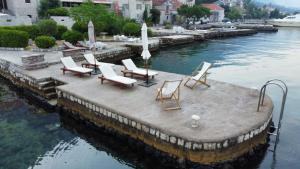 a group of chairs sitting on a dock in the water at Lazovic- Apartment by the Sea with Amazing View in Dobrota