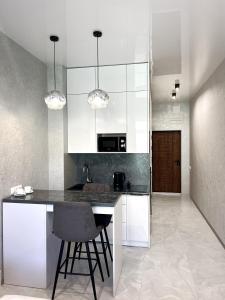 a kitchen with white cabinets and a black counter top at VEM Apartment Калипсо in Odesa