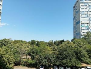 a tall building with cars parked in a parking lot at Apartament ALBATROS in Burgas City