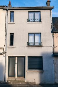 a building with three windows and a door at Appartement cosy au cœur du village - Le Ségala in Montbazens