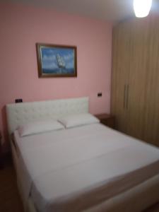 a bedroom with a white bed with a picture on the wall at Vila Tahiri 4 in Golem