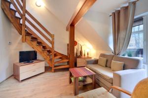 a living room with a couch and a staircase at Apartamenty Sun Seasons 24 - Rezydencja Parkowa in Szklarska Poręba