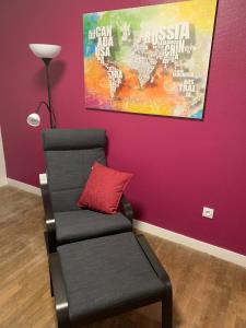 una sedia con un cuscino rosso accanto a un muro viola di Renovated French Country Bungalow for Two - A Home for Your Next Holiday a Hercé