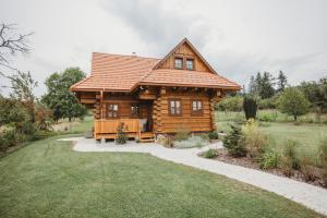 a log cabin with a porch in a yard at Drevenica Liptovské Behárovce in Liptovské Beharovce