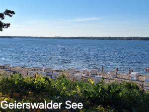 a beach with chairs and people on the water at Lausitzer Auszeit in Laubusch