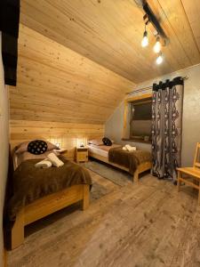 two beds in a room with wooden walls at Leśne Zacisze & Spa na wyłączność in Lubień