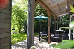 a screened in porch with a table and an umbrella at 400 meter van het strand nieuwe luxe zomerwoning Oostkapelle in Oostkapelle