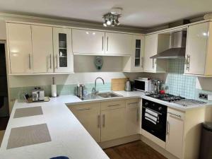 a white kitchen with white cabinets and a sink at One bed flat close to Exeter centre in Exeter