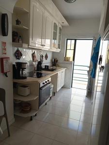 a kitchen with white cabinets and a white tile floor at Tavira sweet home in Tavira