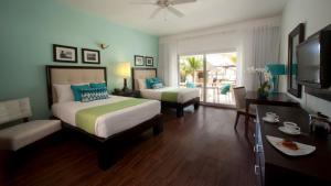 a bedroom with two beds and a television and a balcony at Sandy Haven Resort in Negril