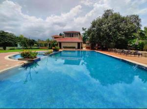 a large pool with blue water in front of a house at Serene 43, Karjat 3 BHK Villa, Wifi, Plunge Pool in Karjat