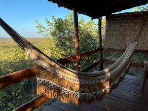 a hammock on a deck with a view of a field at Pousada Bambuí Terra Ronca in São João