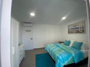 a white bedroom with a bed and a blue rug at DyLary in Armação de Pêra