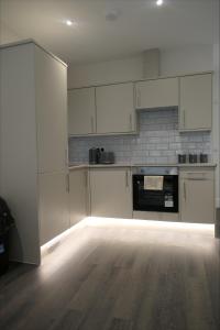 a kitchen with white cabinets and a wooden floor at Exclusive London Apartment - Wembley Stadium, OVO Wembley Arena in London