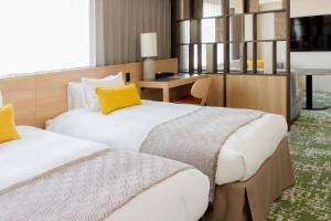 a hotel room with two beds and a desk at Hotel Terrace the Garden Mito in Mito