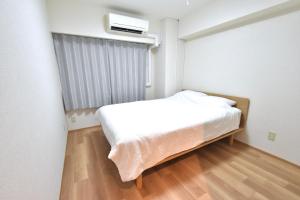 a small bedroom with a white bed and a window at NIYS apartments 01 type in Tokyo