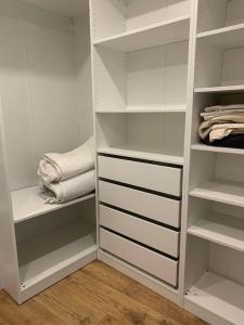a white closet with white shelves and towels at Appartement Douillet Central - Parking Inclus in Manosque