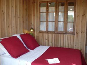 Una cama con sábanas rojas y blancas y una ventana en La Cabanote, en Biscarrosse