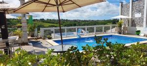 a pool with an umbrella and a table and chairs at Pousada Rota do Pilão in Araçoiaba +50 photos