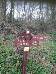 a wooden sign in the middle of a forest at Maison des 2 Grottes in Estadens