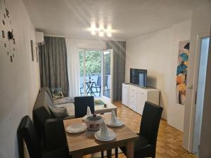 a living room with a table and a room with a bed at Apartman Atina Doboj in Doboj