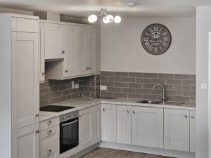 a kitchen with white cabinets and a clock on the wall at Brogans Apartments in Trim