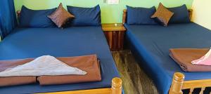 two beds in a room with blue sheets at Srujana Beach Homestay in Gokarn +100 photos