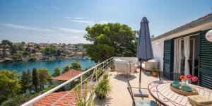 a balcony with an umbrella and a view of a river at Holiday Home Dora in Splitska